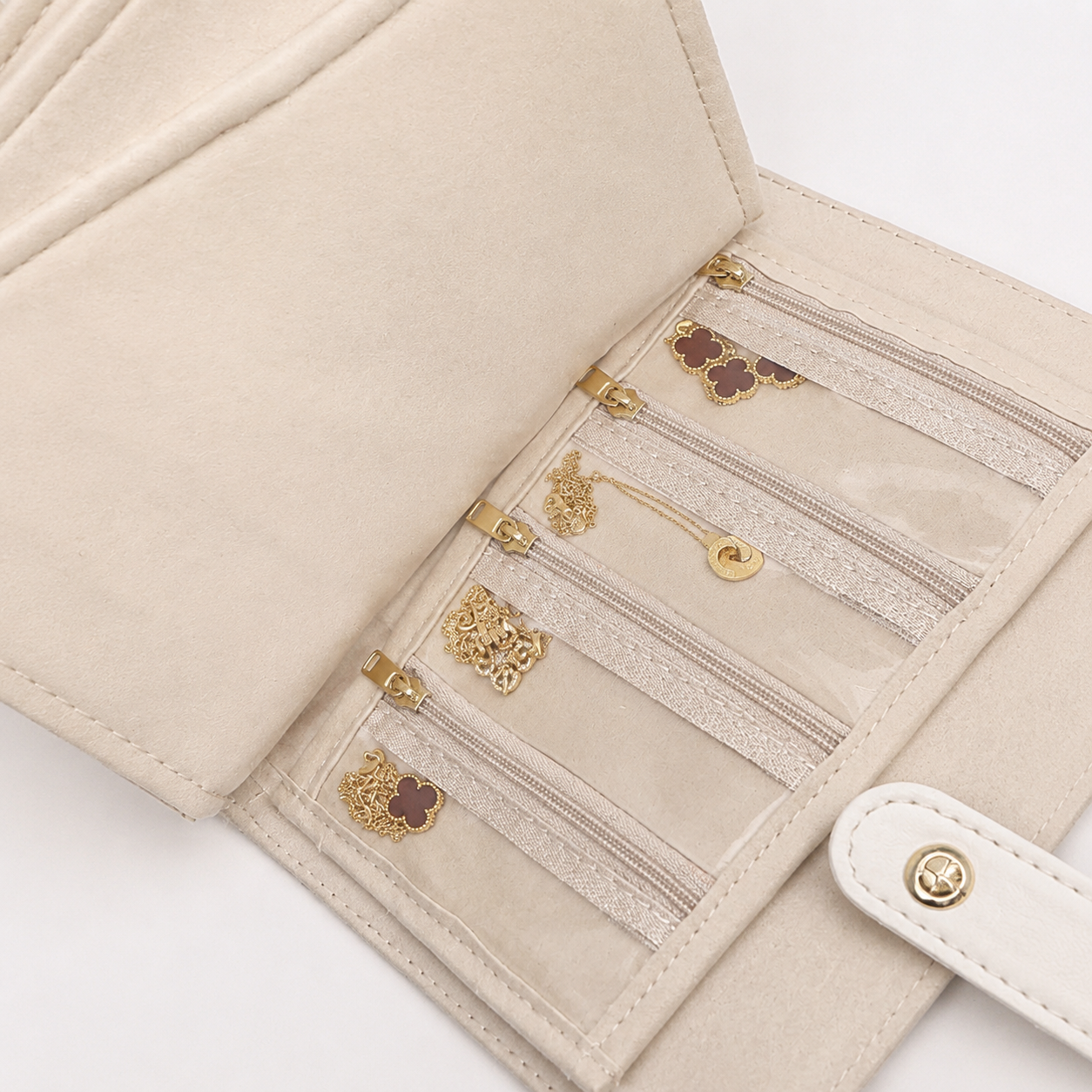 Close-up of clear zip pockets holding small jewelry inside the travel jewelry organizer book