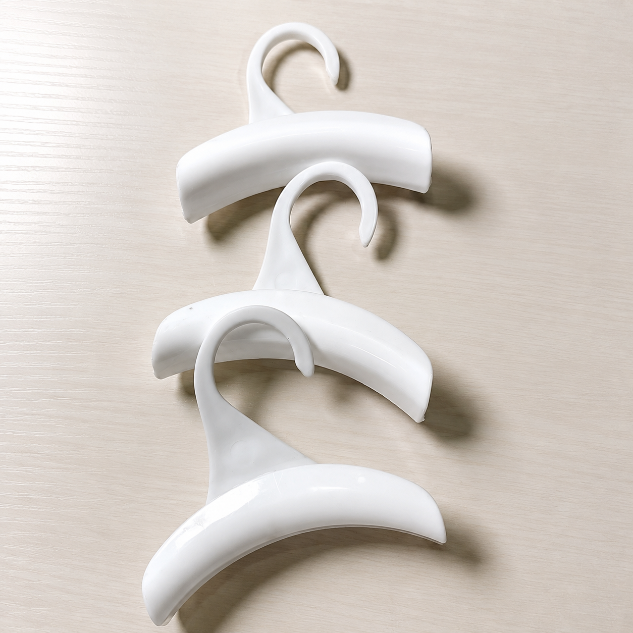 Three white closet accessory hooks arranged as a set