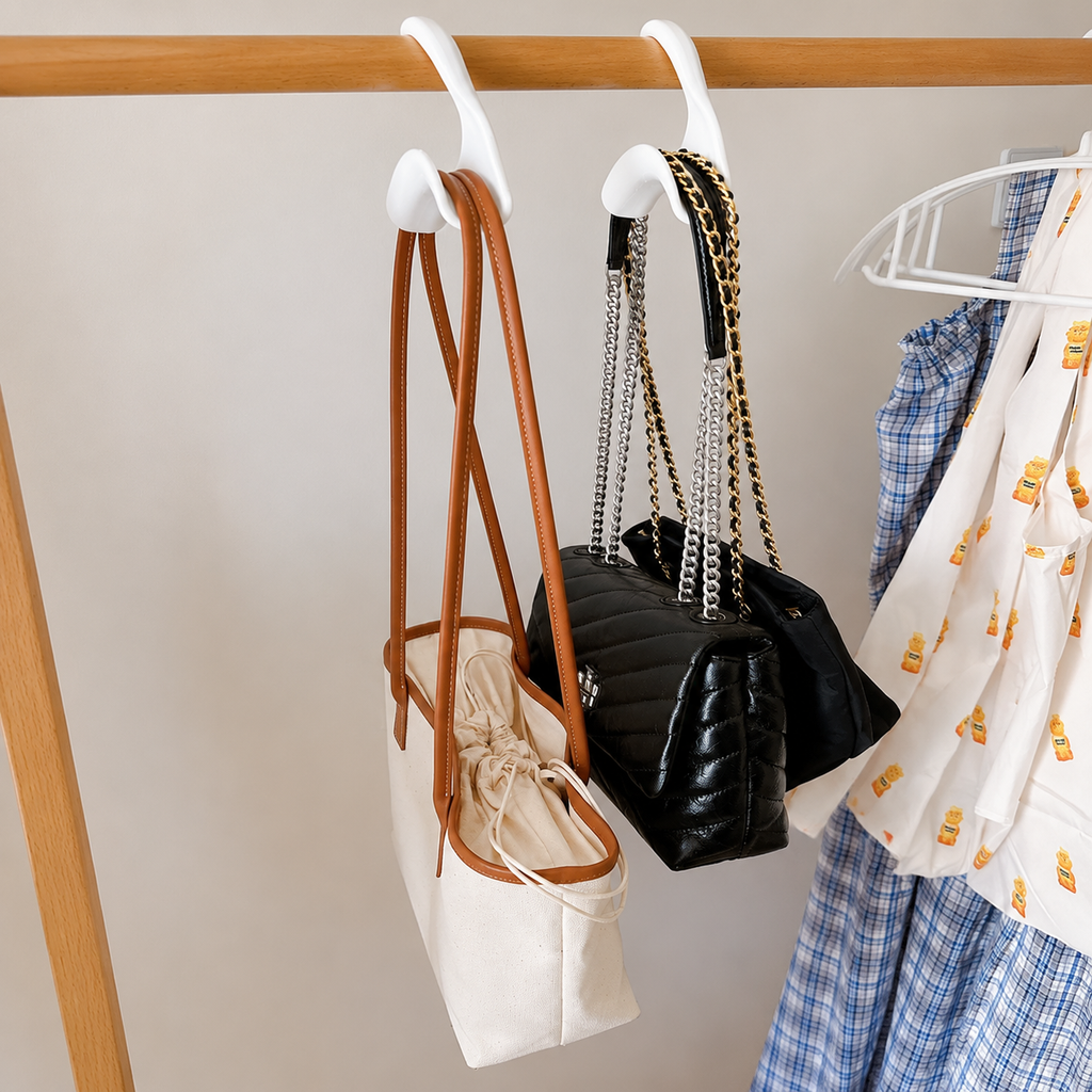 Purse straps resting in white closet hook saddles on a rail
